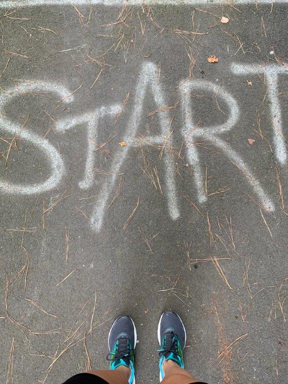 Pavement with START written on it and view of my running shoes.