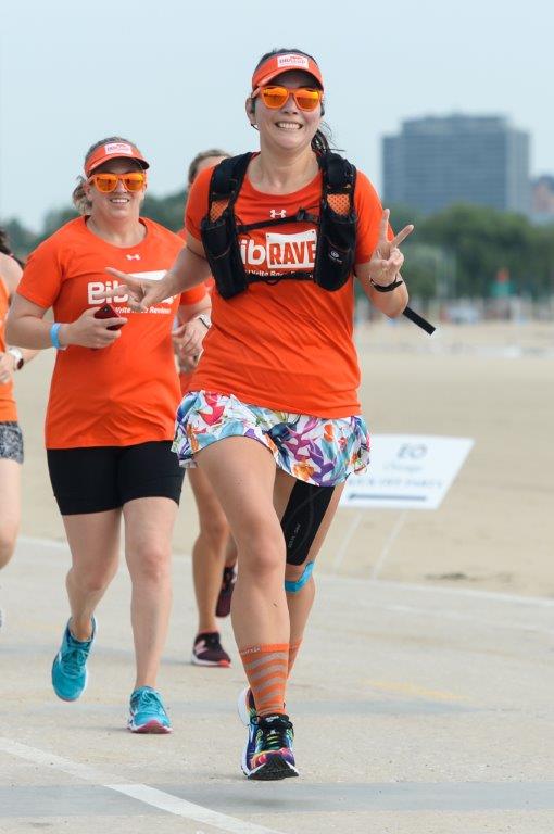 Running by Lake Michigan with skyline behind. Wearing BibRave orange shirt.