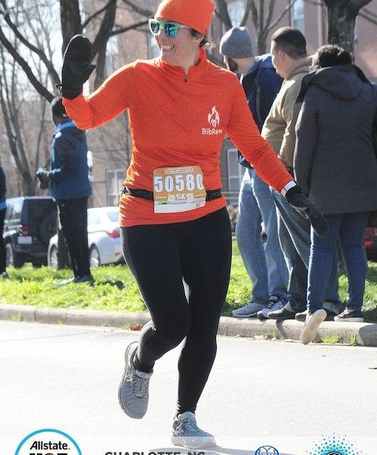 Wearing my BibRave orange shirt and beanie as I cross the finish line at the Hot Chocolate 15k.