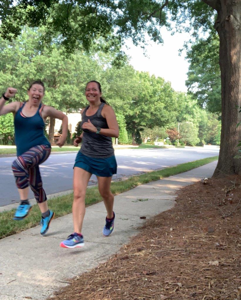 Running on a neighborhood street with my friend who is leaping into the air.