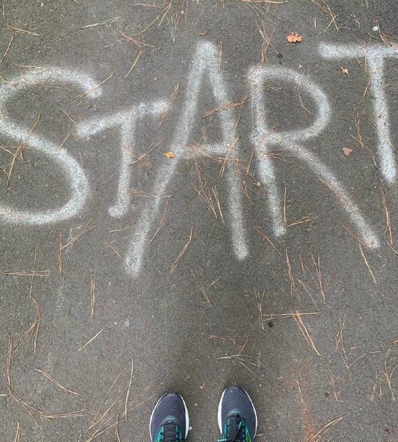 Pavement with START written on it and view of my running shoes.