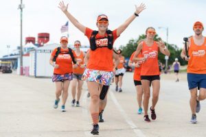 Running with the BibRave team in all orange with my arms outstretched in victory.