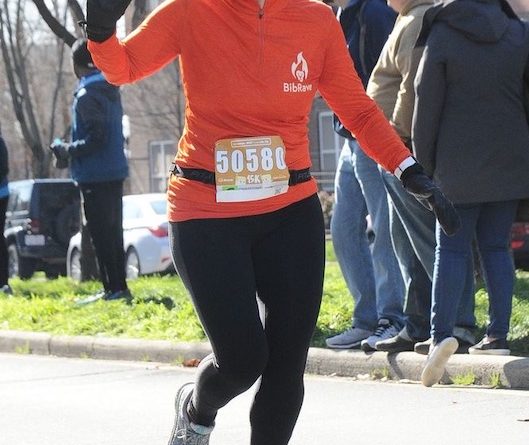 Wearing my BibRave orange shirt and beanie as I cross the finish line at the Hot Chocolate 15k.