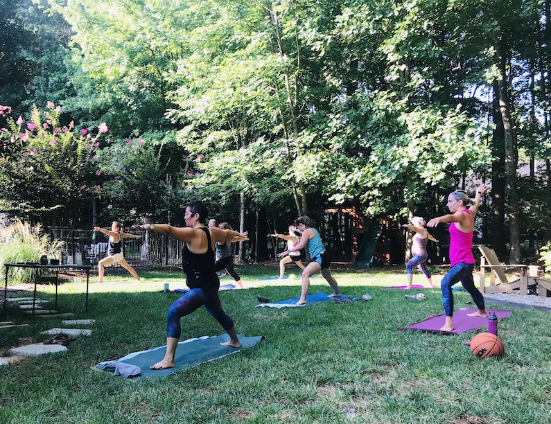 Teaching a group of students spaced out in my backyard doing the pose, Warrior 2.